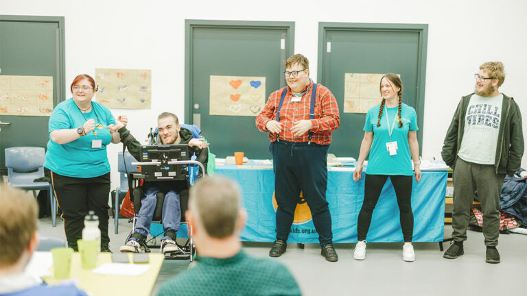 Three young people and two staff members give a presentation to an audience.