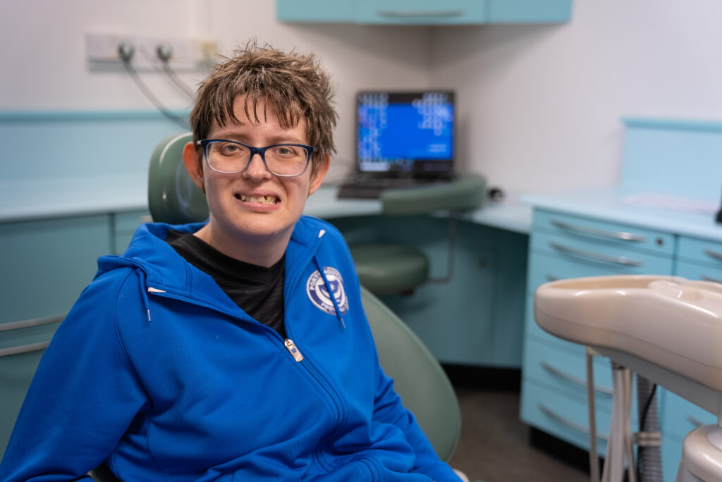 Carly sits in a dentist's chair smiling